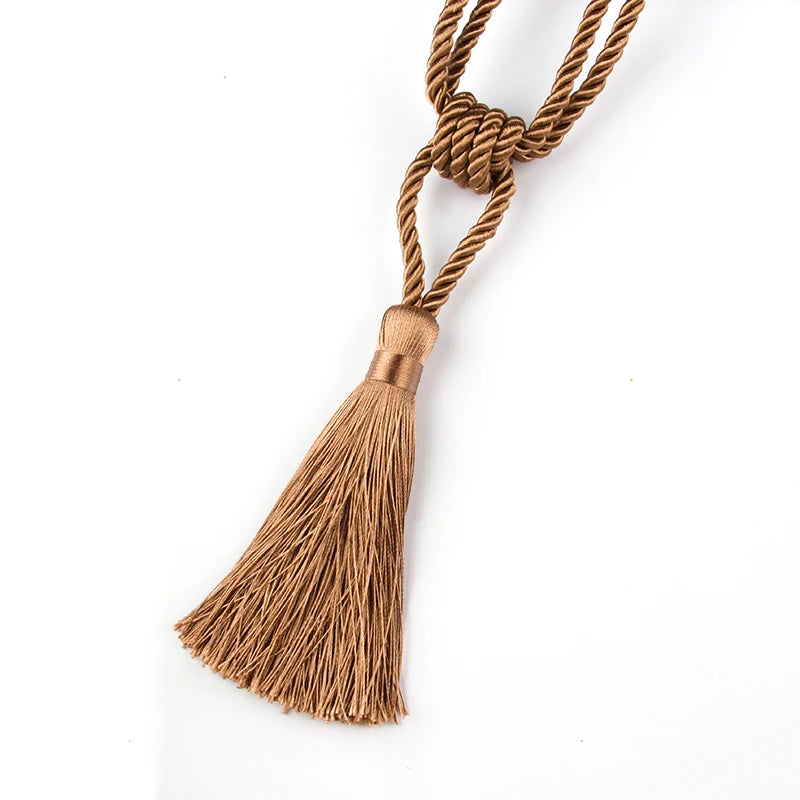 A set of two elegant gold-brown tassel curtain tiebacks made of twisted rope.