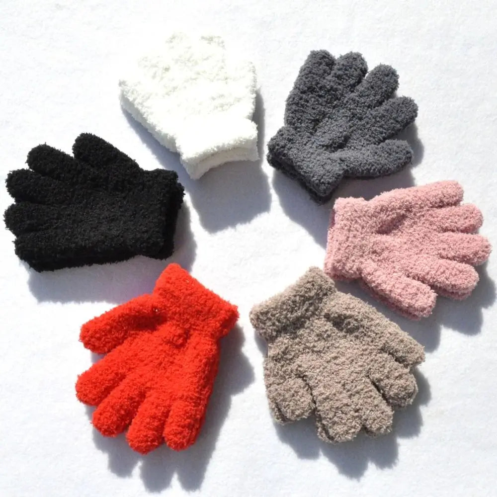 A collection of five plush winter gloves in black, gray, white, pink, and orange colors arranged in a circle on a white backg