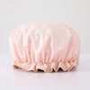 A light pink reusable elastic shower cap with gold star embroidery.