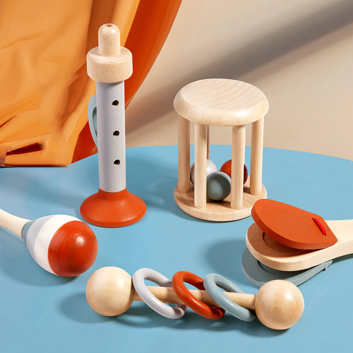A collection of wooden baby rattles and a wooden teething ring are displayed on a blue surface.