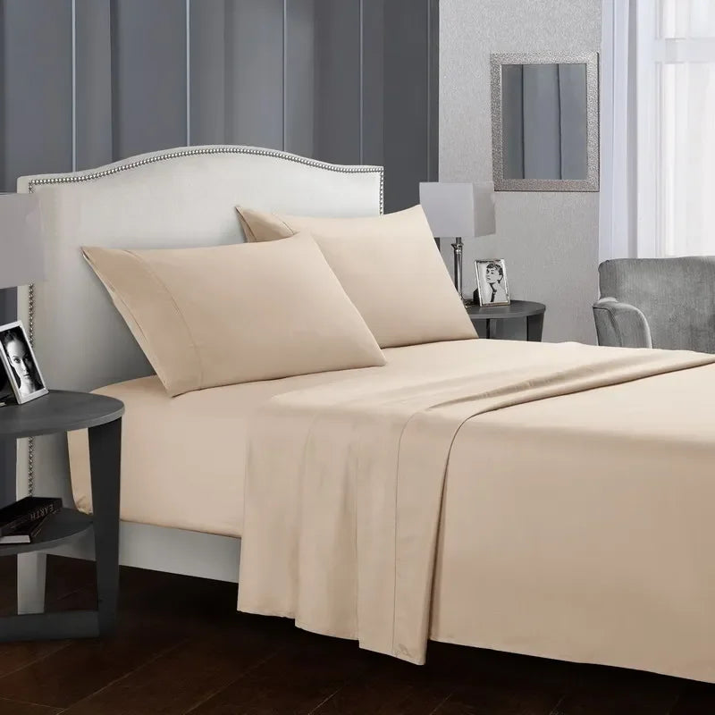 A beige bedding set featuring a fitted sheet, flat sheet, and pillows on a bed with a upholstered headboard.