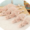 A collection of soft pink and beige dragon plush pillows arranged on a light-colored surface.