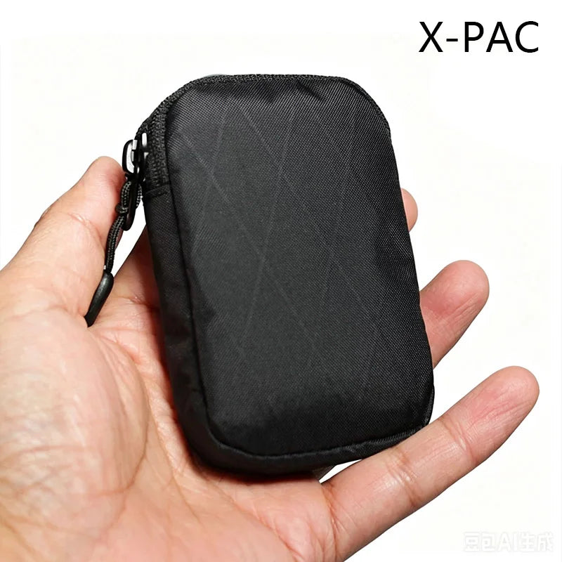 A hand is holding a black X-PAC compact EDC utility pouch.
