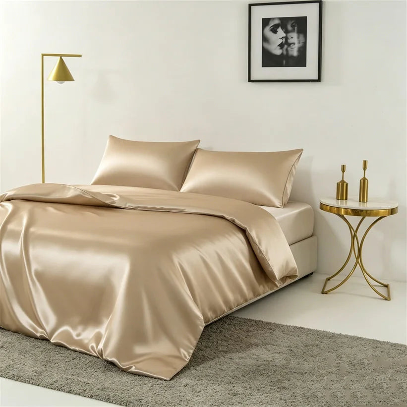 A luxurious champagne silk duvet cover set displayed on a bed with gold accents and a framed black and white photograph.