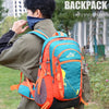 A person wearing a olive green jacket is adjusting an orange and teal backpack outdoors.
