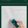 A hand is using a green eraser to remove wall stains from a white surface.