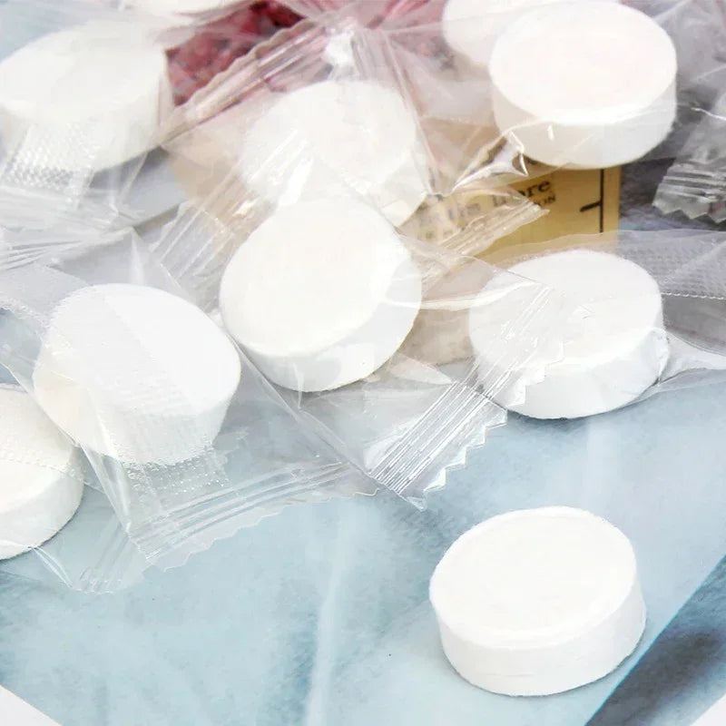 A collection of white portable compressed cleansing towels packaged in clear plastic bags.