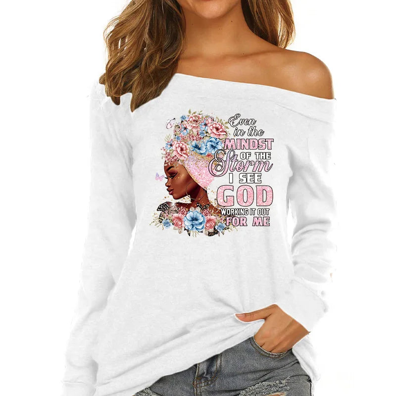 White long-sleeve shirt with a pink and floral graphic featuring the text Even in the midst of the storm I see God working it