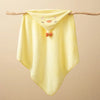 Yellow hooded baby bathrobe towel with a cartoon duck face design hanging on a wooden branch