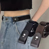A close-up of a black elastic belt with silver buckles and a dark brown strap, worn around the waist of a person wearing deni