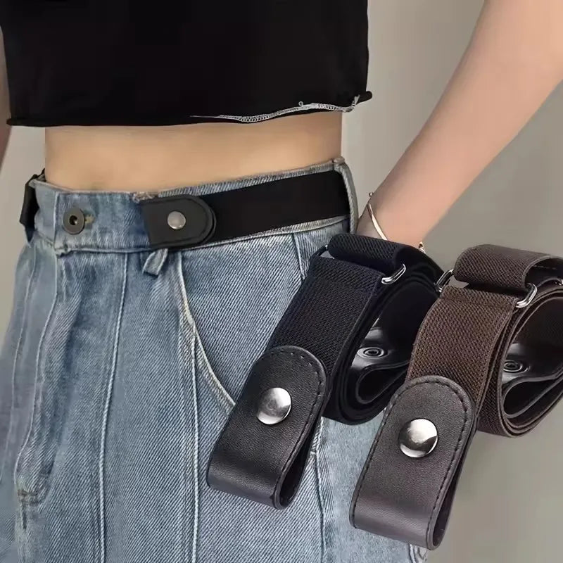 A close-up of a black elastic belt with silver buckles and a dark brown strap, worn around the waist of a person wearing deni