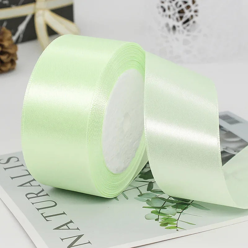 A roll of light green satin ribbon used for gift wrapping or DIY crafts.