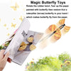 A hand holds a paper butterfly toy demonstrating how to restore a butterfly from a caterpillar using a rubber band.