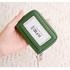 A close-up of a green RFID shielded accordion wallet with a gold chain attached, shown being held by a hand.
