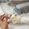 A hand holds a clear jewelry organizer box filled with light yellow and gray beads, next to a tray of clear compartments.