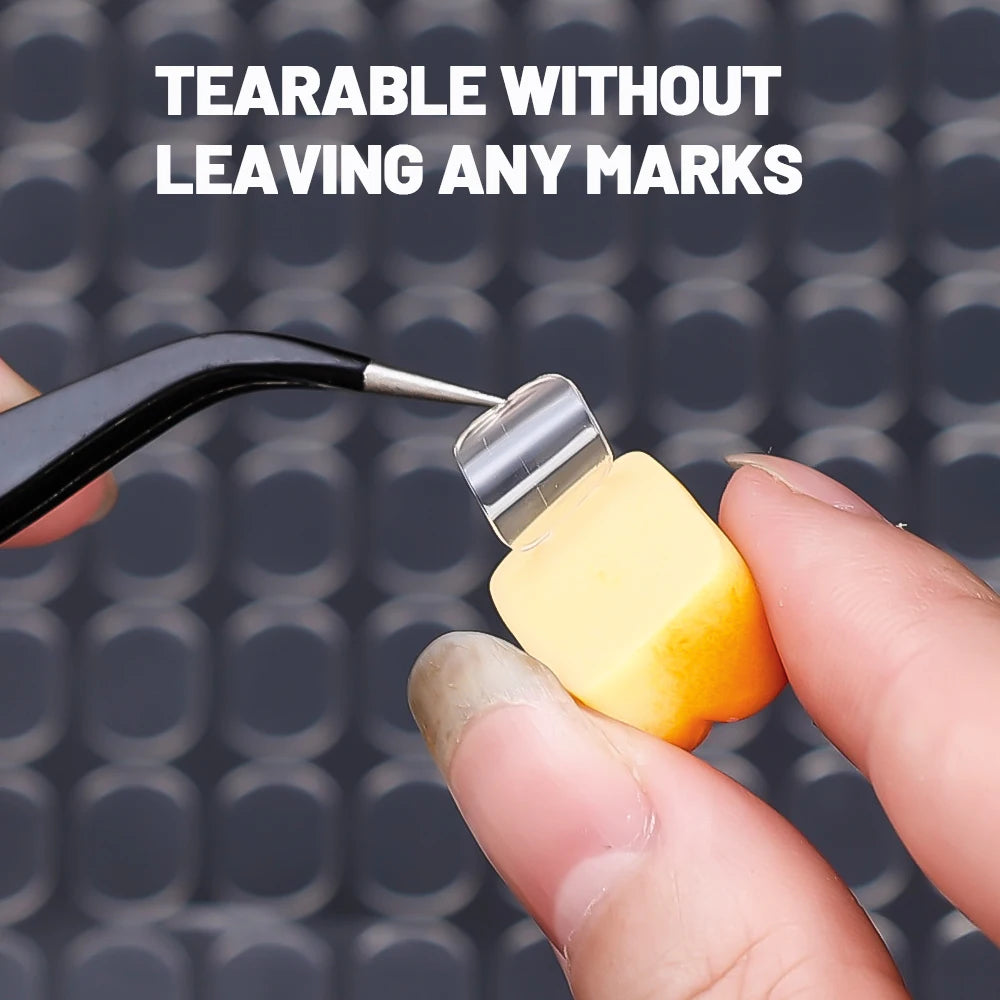 A hand applies a double-sided transparent adhesive patch to a surface, demonstrating its tearable quality.