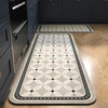 A long rectangular kitchen rug with a gray and black classic Persian pattern placed on a wooden floor.