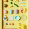 A yellow tray holds various colorful plastic kitchen and fishing toys for children.