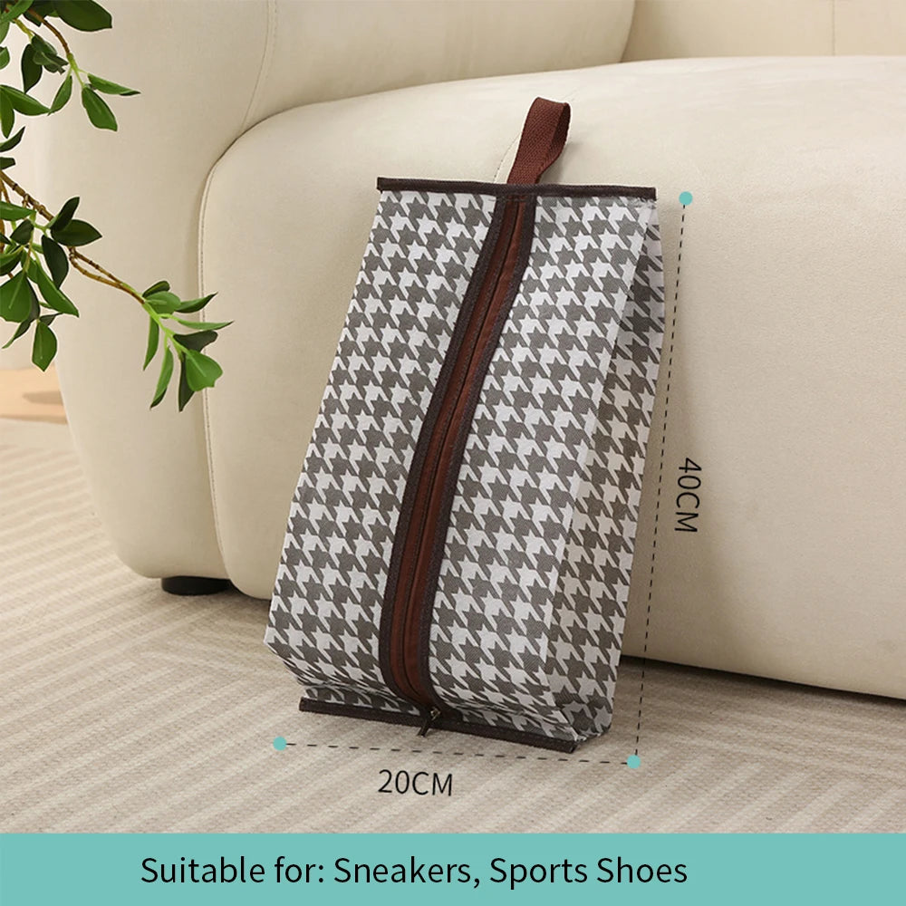 A gray and white patterned waterproof boot storage bag with a brown handle resting on a light-colored sofa.