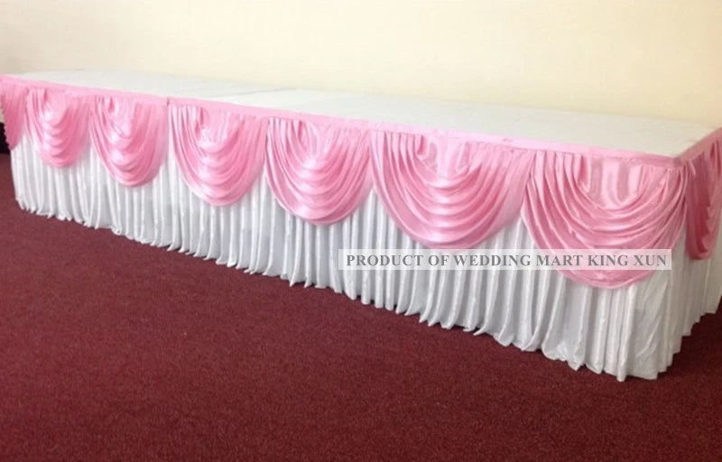 Elegant ice silk table skirt with matching top swag in pink and white fabric displayed on a red carpet.