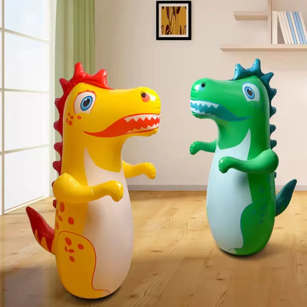 A yellow inflatable standing boxing punching bag and a green inflatable crocodile toy on a wooden floor.