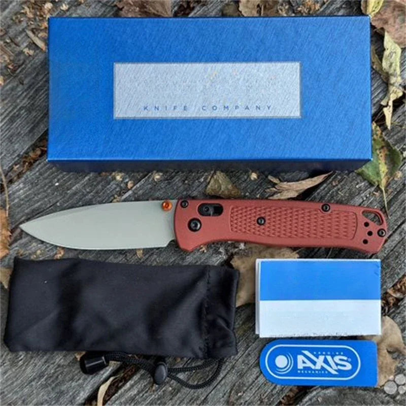 A blue box, a folding knife, and a sheath are displayed on a wooden surface.