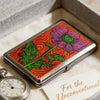 Vintage metal card and cash case with an art deco design featuring a pink flower on a red background.