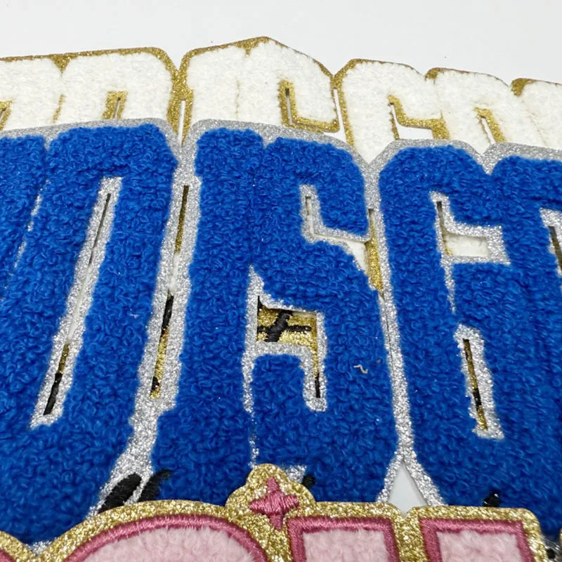 Embroidered chenille iron-on patch featuring the text God Is Good in blue and gold thread.