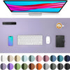 A computer monitor displaying colorful graphics is shown above a purple desk pad with various office accessories.