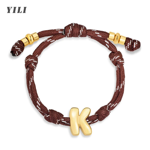 Bracelet tressé marron avec nœud doré et charm initial K doré.