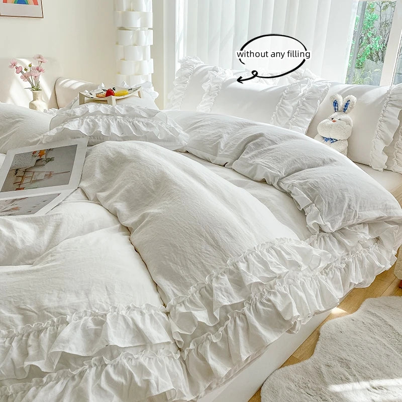 A white ruffled duvet cover set with pillows and a decorative stuffed animal on a bed.