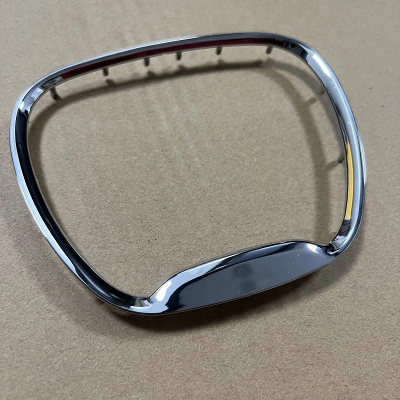 A chrome steering wheel cover with an emblem, shown against a brown background.