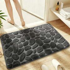 A dark gray plush non-slip absorbent bathroom rug with a pebble texture placed on a wooden floor.