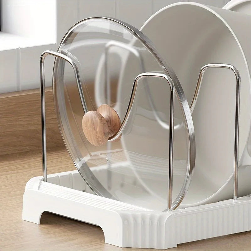 A clear, expandable pot and pan organizer rack with adjustable dividers sits in a white tray.