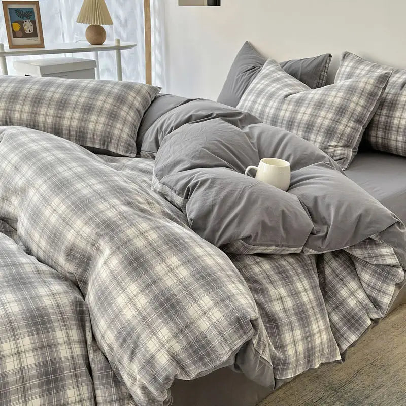 A gray and white plaid bedding set featuring a duvet cover, flat sheet, and pillows on a bed.