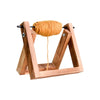 A wooden yarn ball holder with a stable base and a spool of golden-colored yarn.