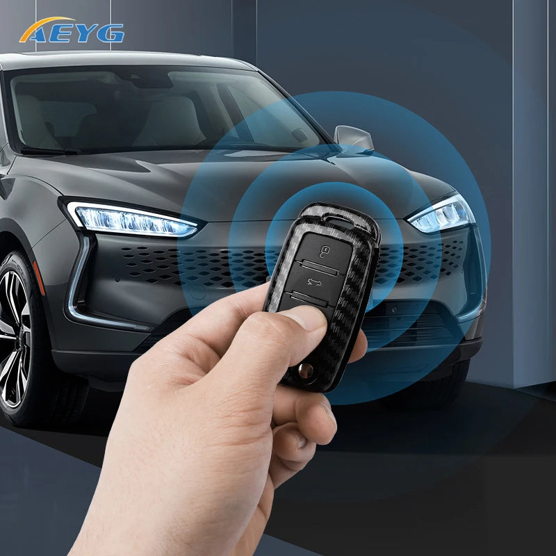 A hand holds a carbon fiber car key cover near the front light of a dark gray VW or Skoda vehicle.