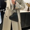 A beige trench coat is shown holding a black heart-shaped PU coin purse with a strap.