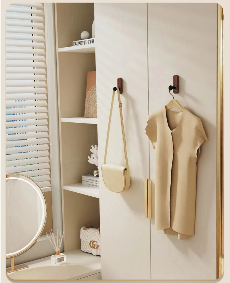 A light beige jacket is hanging on a wooden hook in a modern cabinet with white shelving.