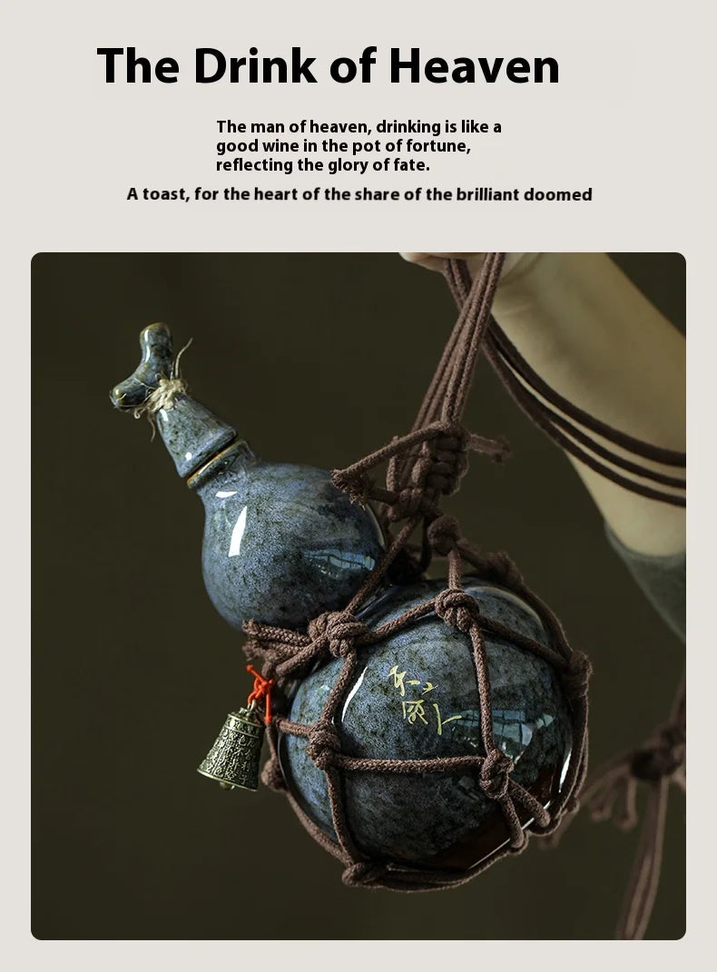 A dark blue ceramic gourd wine set with a net bag is suspended by twine against a dark background.