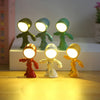 A set of three bendable robot night lights with soft glow illuminating a wooden surface.