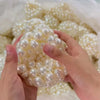 Eine Hand hält eine Ansammlung weißer Perlen zum Herstellen eines Squishy-Stressballs.