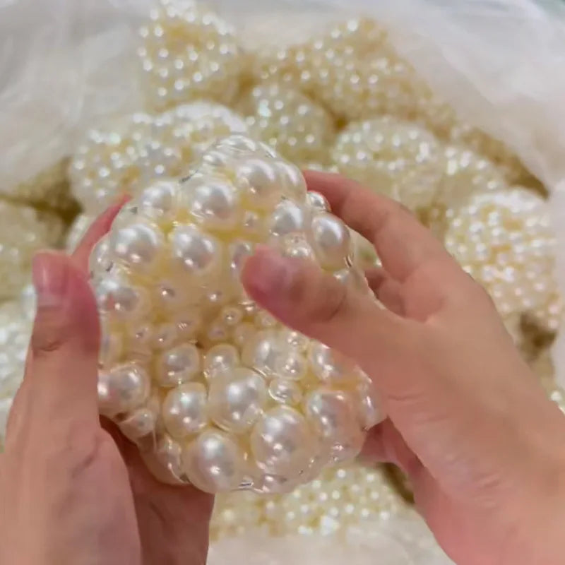 Eine Hand hält eine Ansammlung weißer Perlen zum Herstellen eines Squishy-Stressballs.