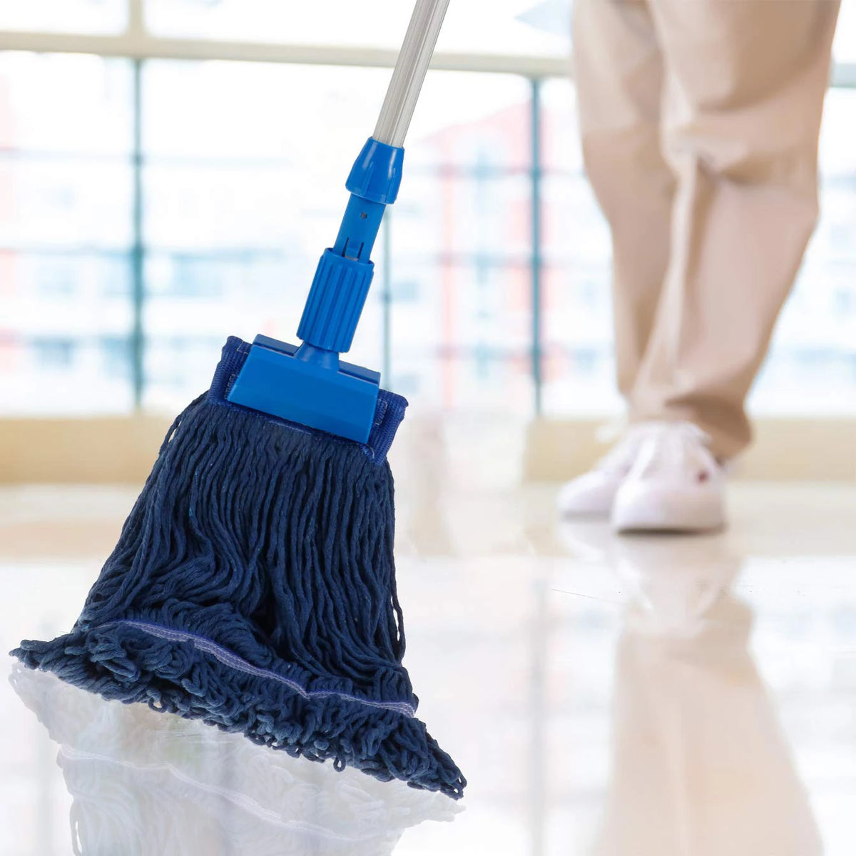 A blue heavy-duty cotton string mop head replacement being used on a floor.