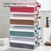 A stack of four soft absorbent quick-dry bath towels in various shades of pink, beige, and blue on a white surface.