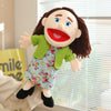 A hand puppet character with dark hair, blue eyes, and red lips wearing a floral dress and green jacket.