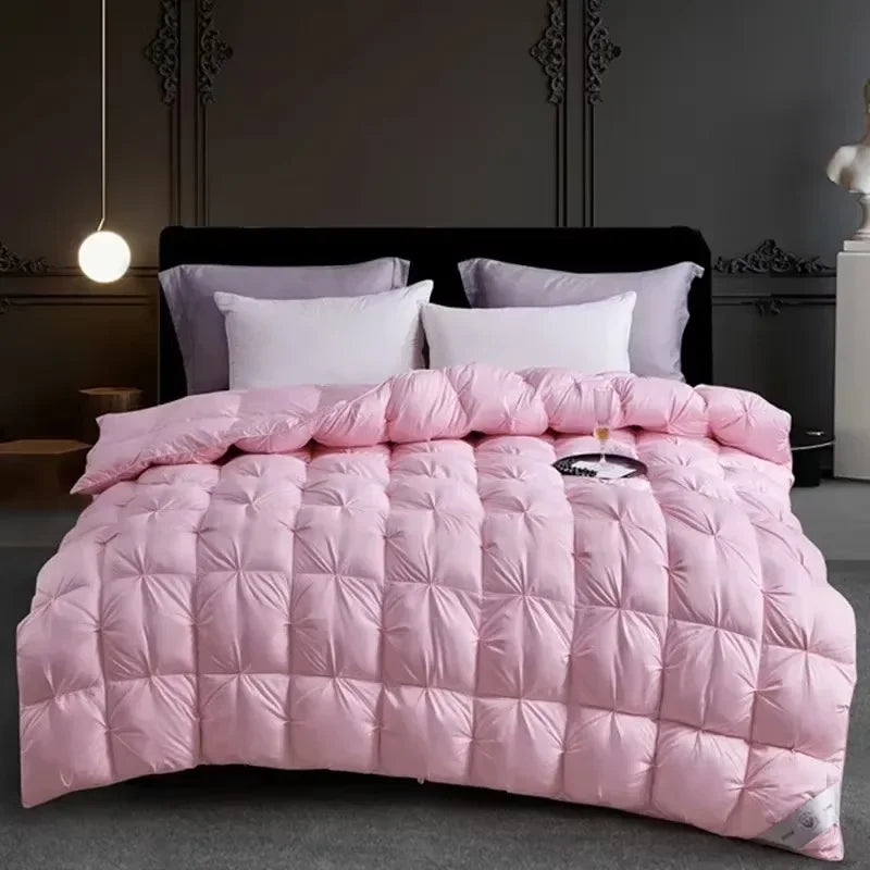 Pink quilted comforter with white pillows displayed on a dark bed against a gray wall.
