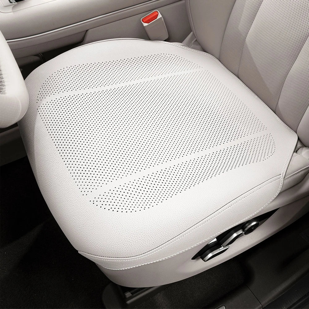 A white breathable leather car seat cushion is shown in a close-up view.