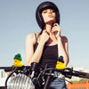 A woman wearing a black helmet and top is posing with a yellow rubber duck car dashboard ornament.