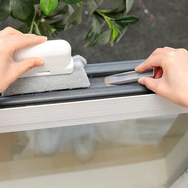 Hands are cleaning a window using a white groove cleaning brush with a replaceable scouring head.